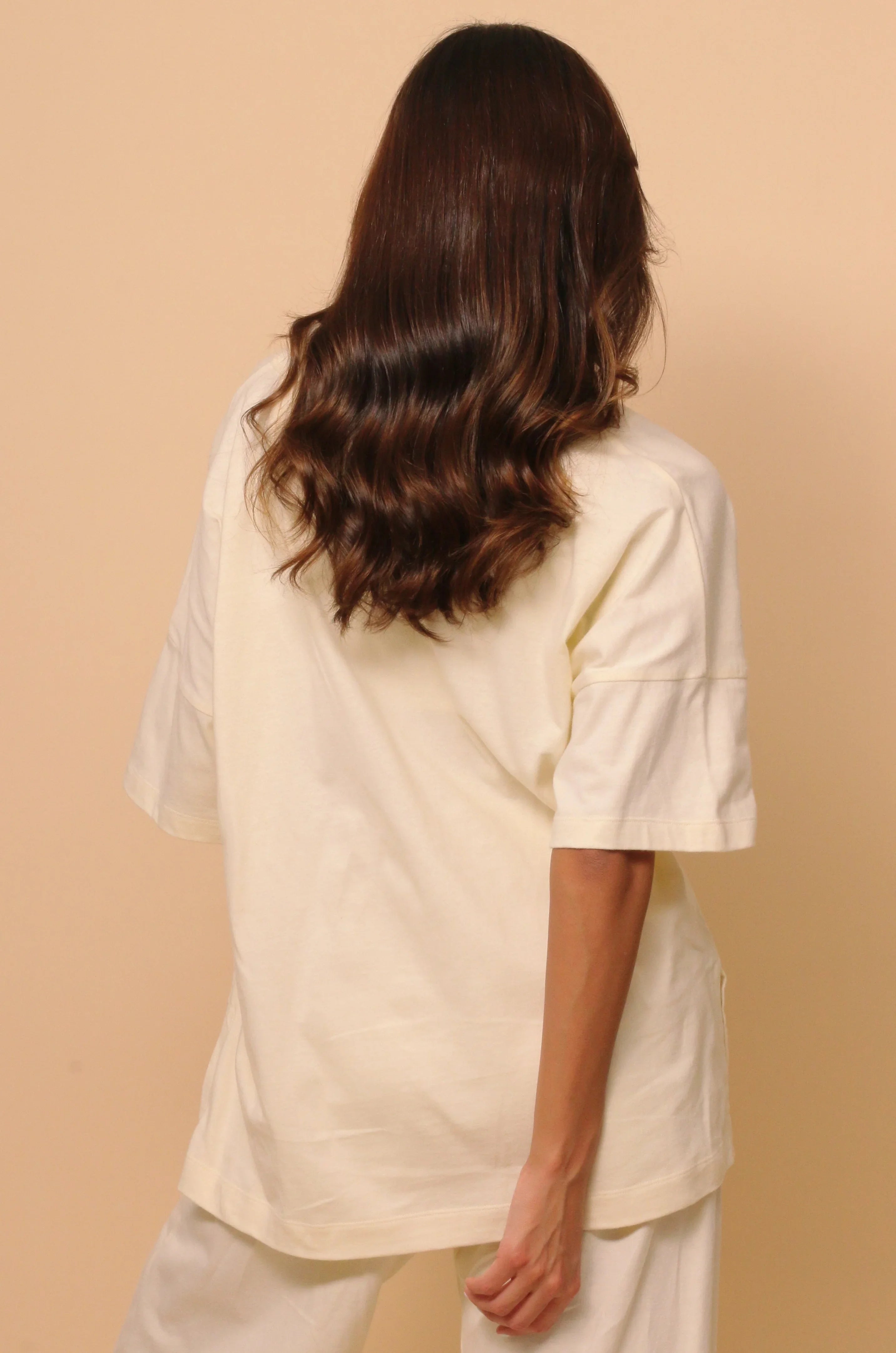 Woman wearing allergy-free Cottonique hypoallergenic ivory shirt and pants, back view.