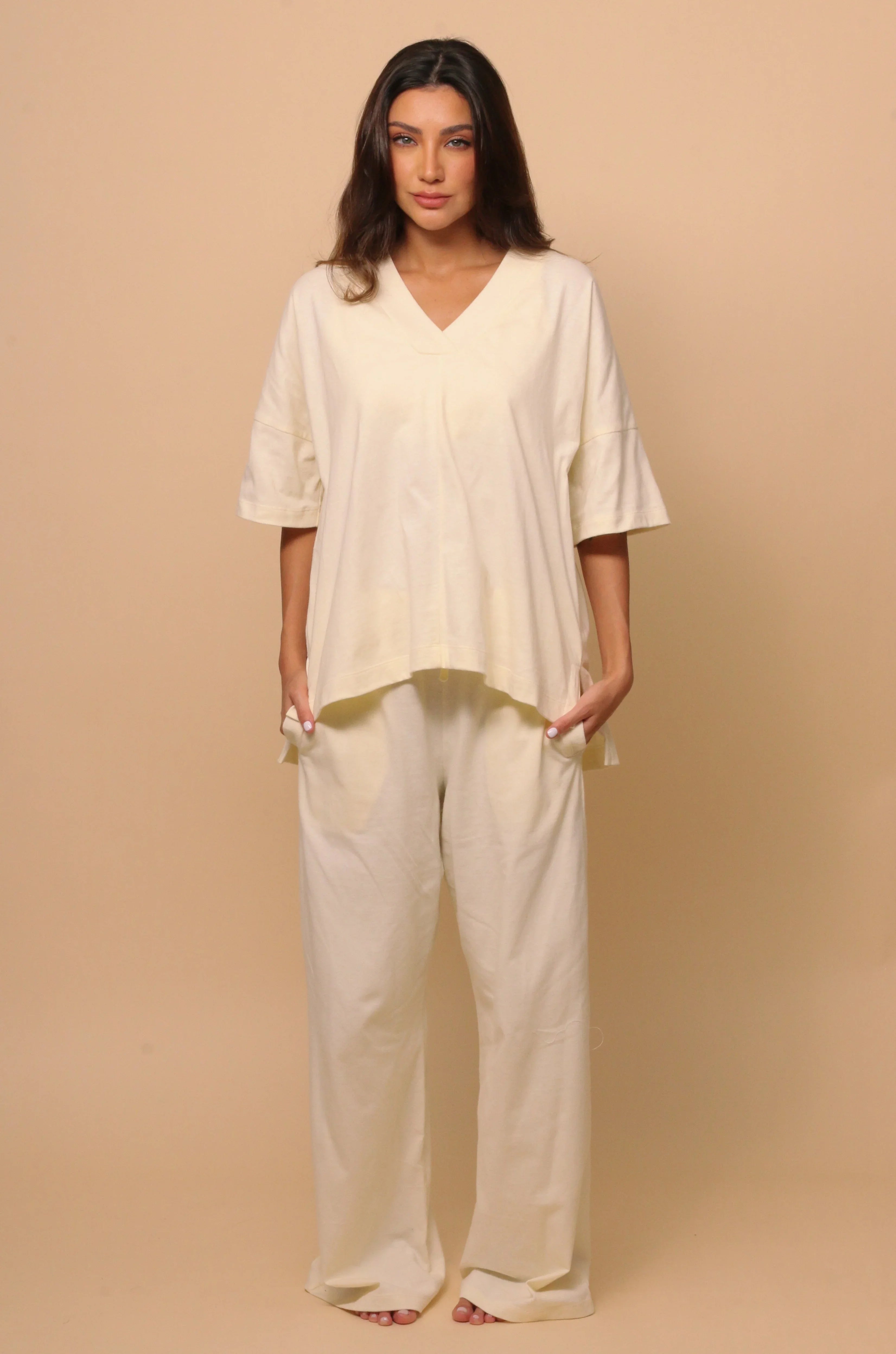 Woman wearing loose-fit, cream hypoallergenic Cottonique loungewear set on neutral background