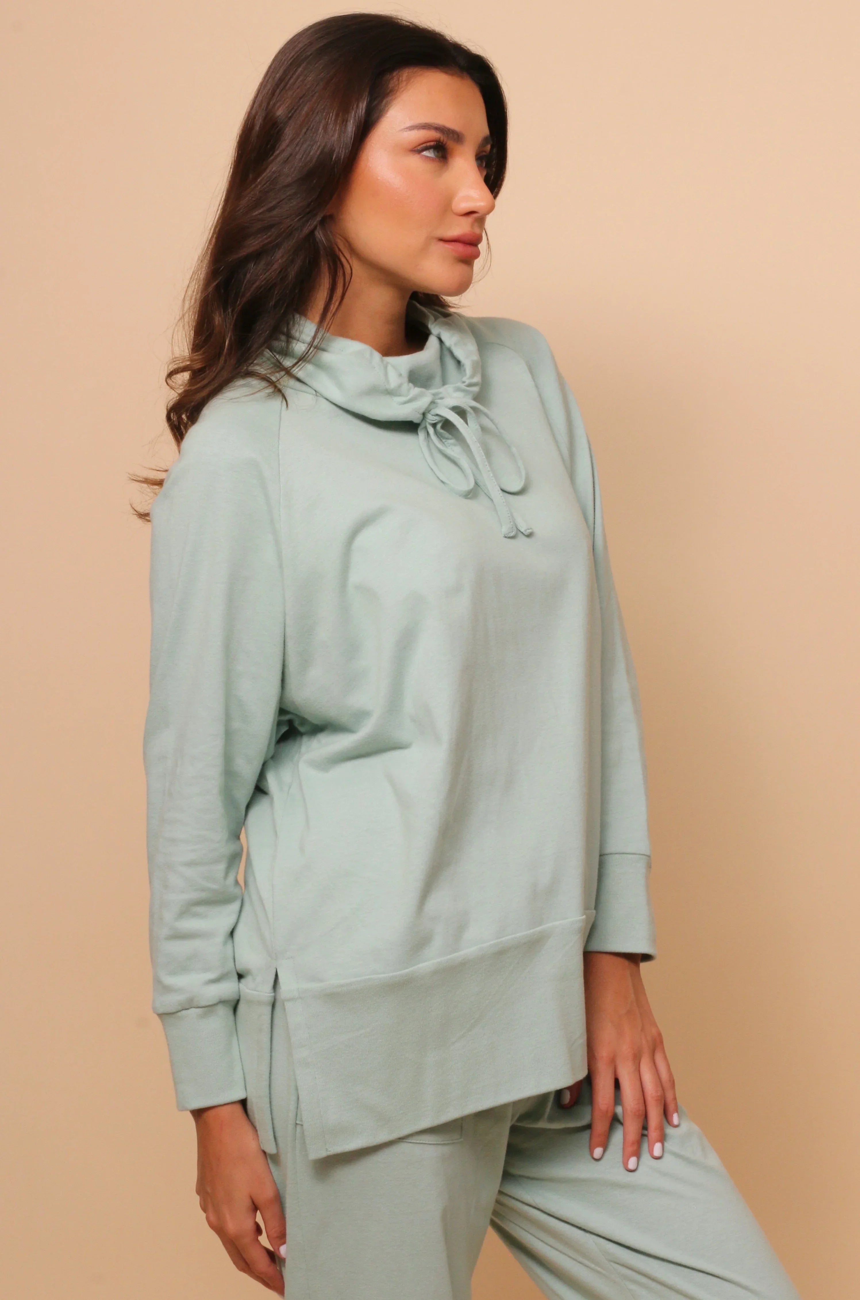 Woman wearing light green hypoallergenic Cottonique pullover with cowl neck and drawstring