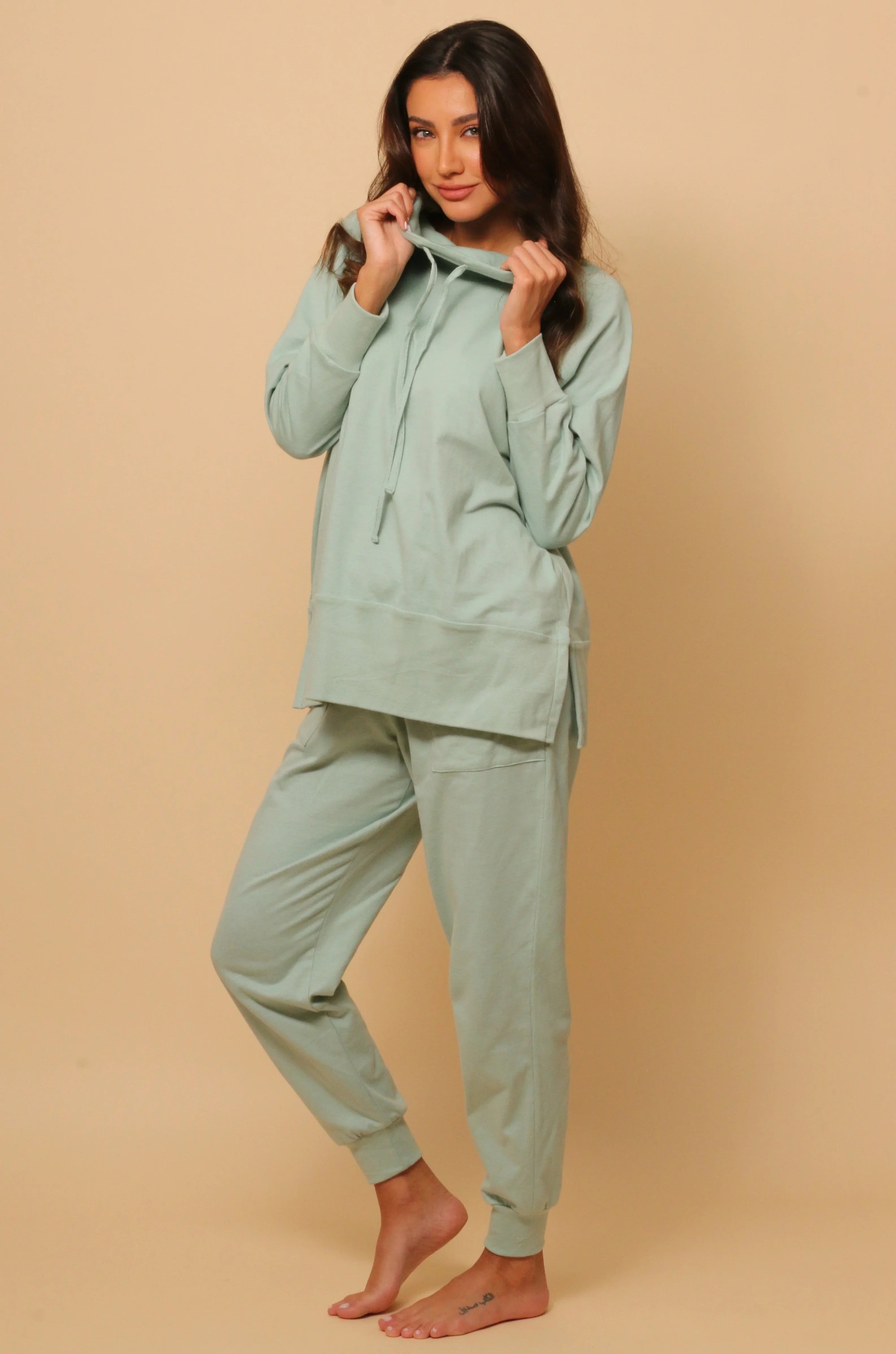 Woman wearing light green hypoallergenic Cottonique lounge set against beige background