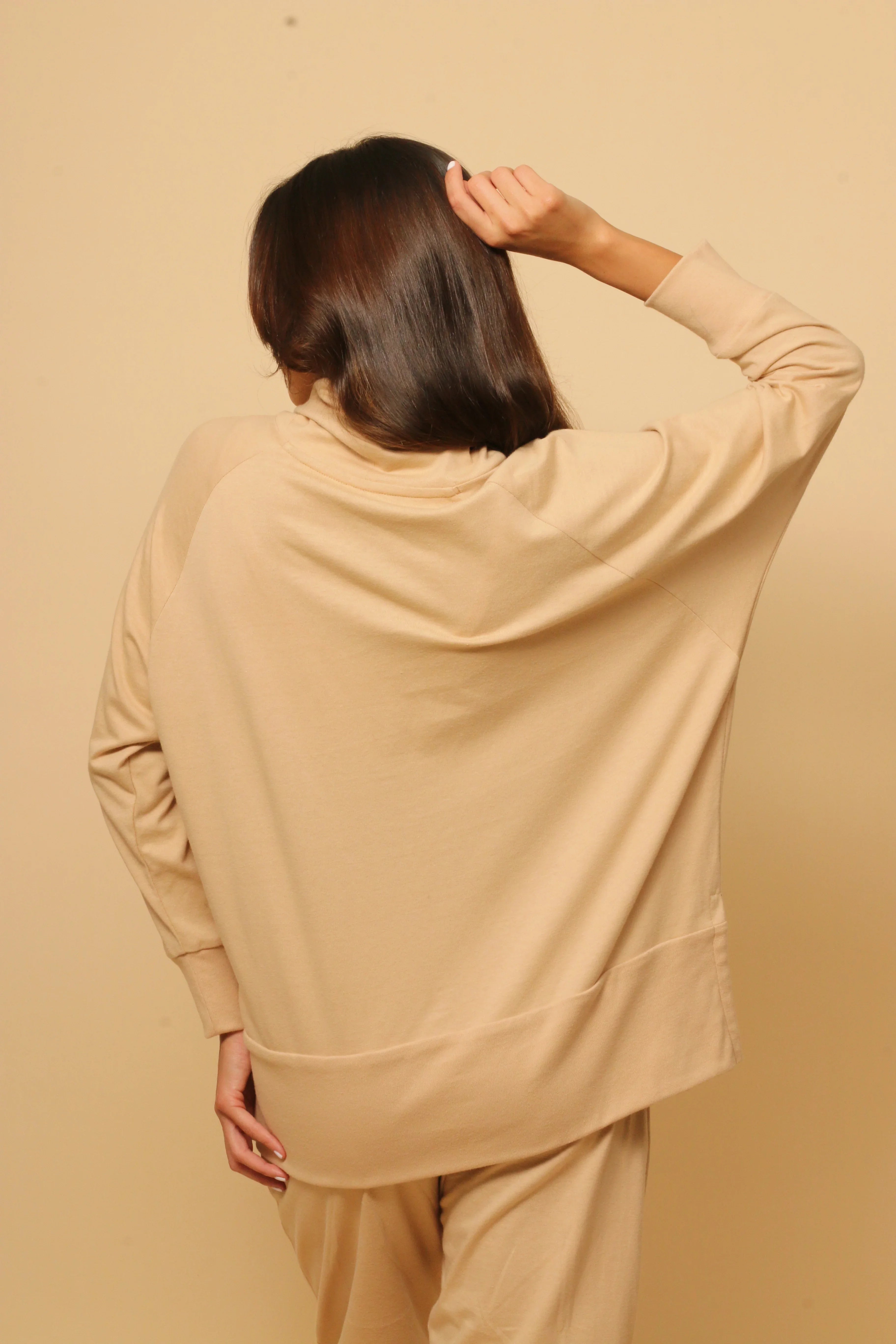 Woman in beige hypoallergenic Cottonique sweatshirt and pants, shown from the back.