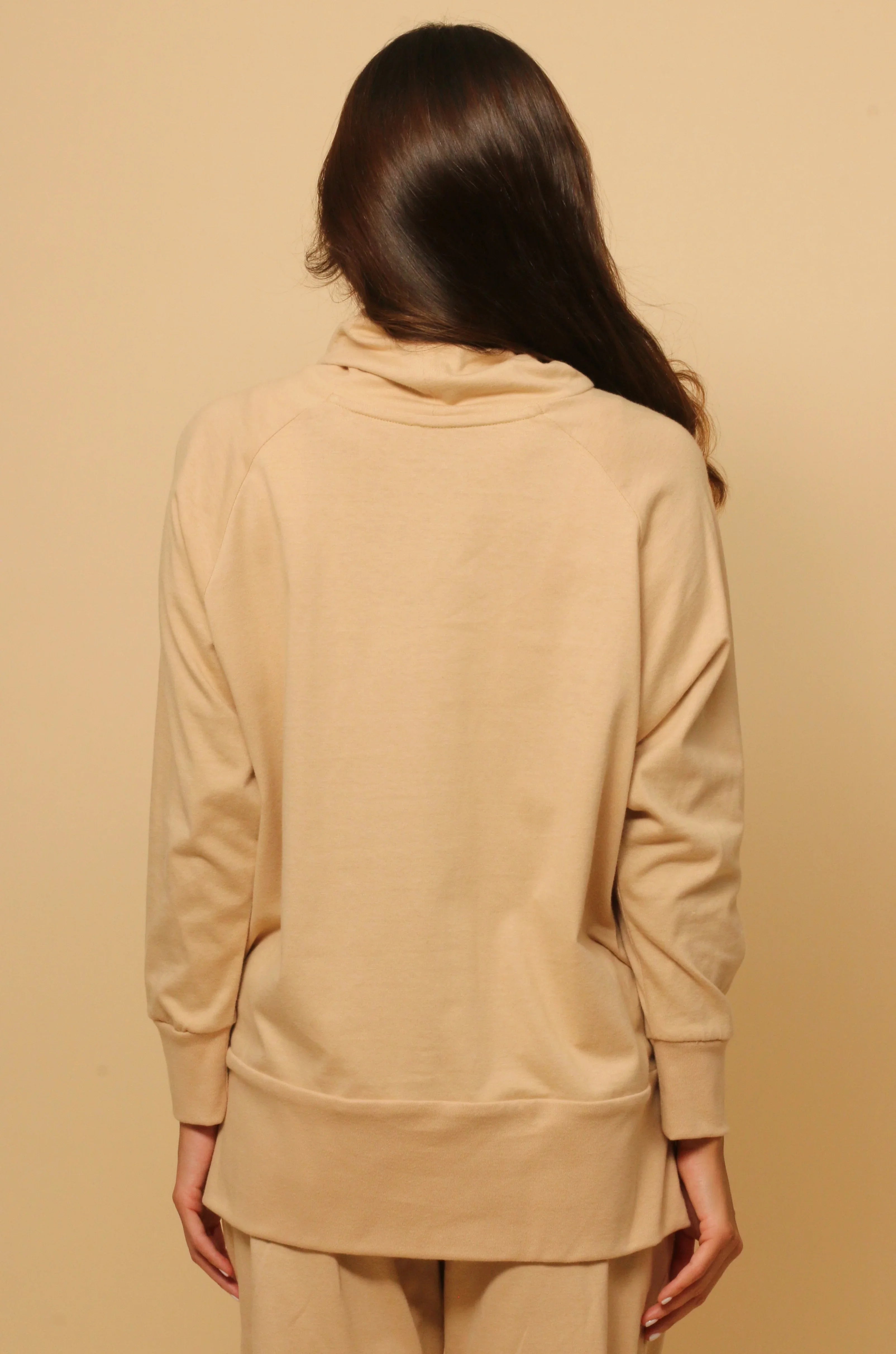 Back view of a woman wearing a beige hypoallergenic cotton sweatshirt and pants