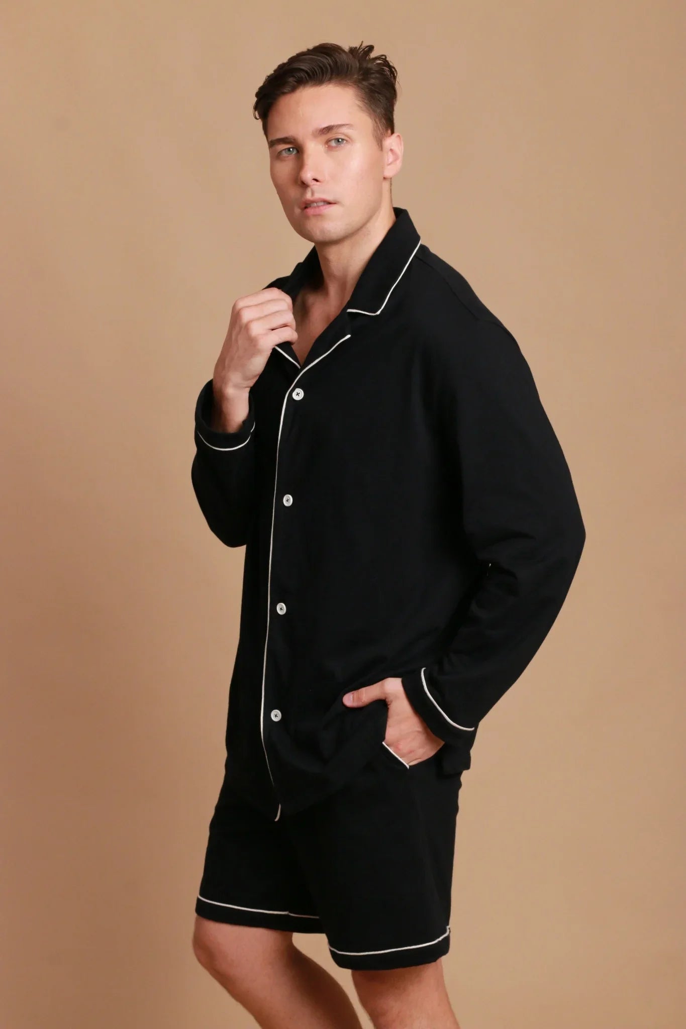 Man wearing black hypoallergenic cotton pajamas with white piping from Cottonique