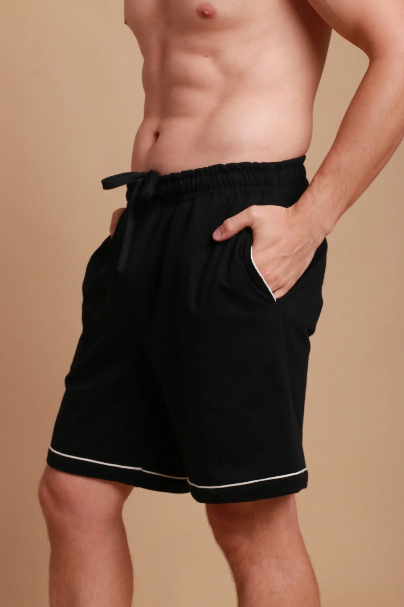 Man wearing black hypoallergenic Cottonique shorts with white trim, hands in pockets
