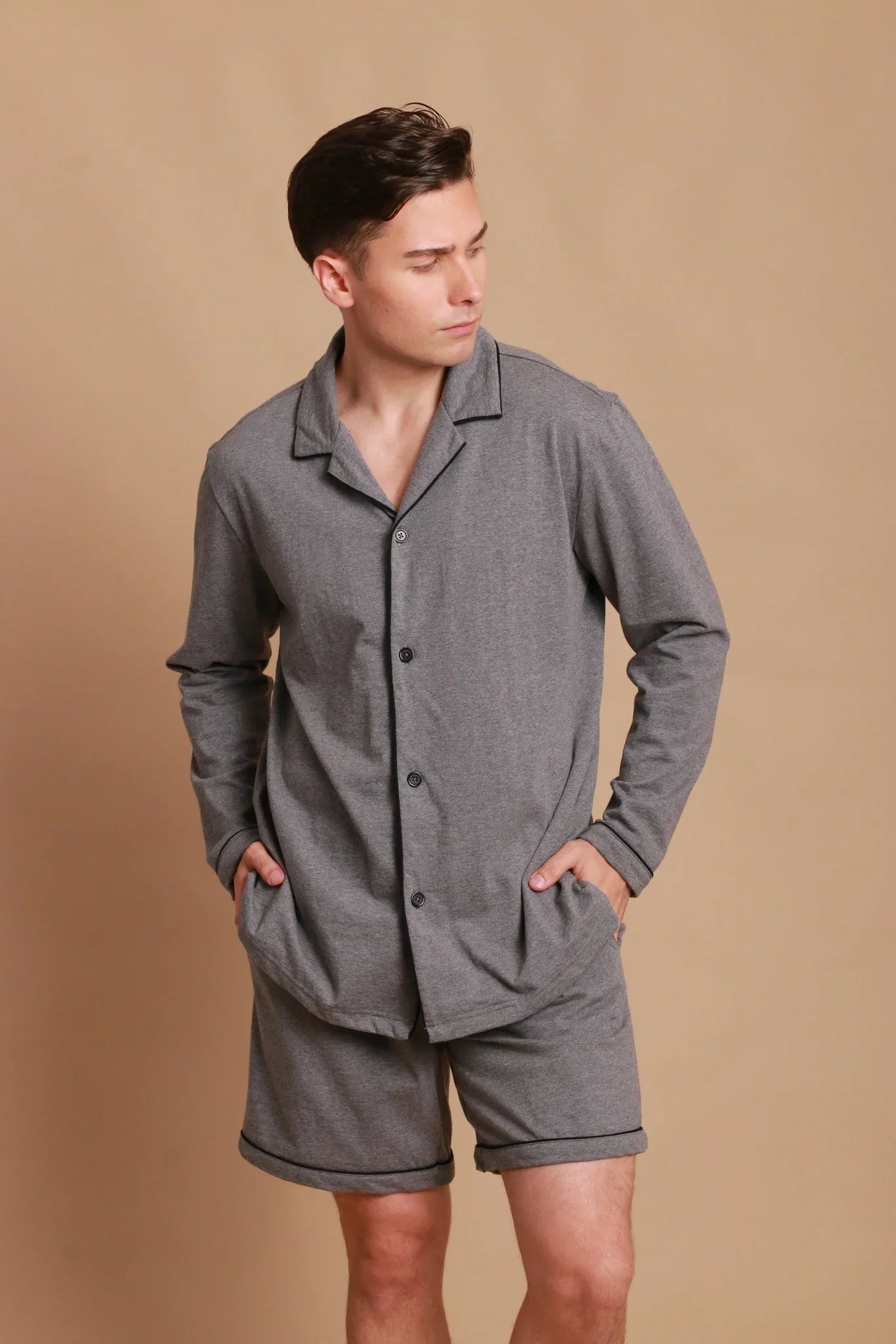 Man wearing gray organic cotton long sleeve pajama set with shorts, suitable for sensitive skin