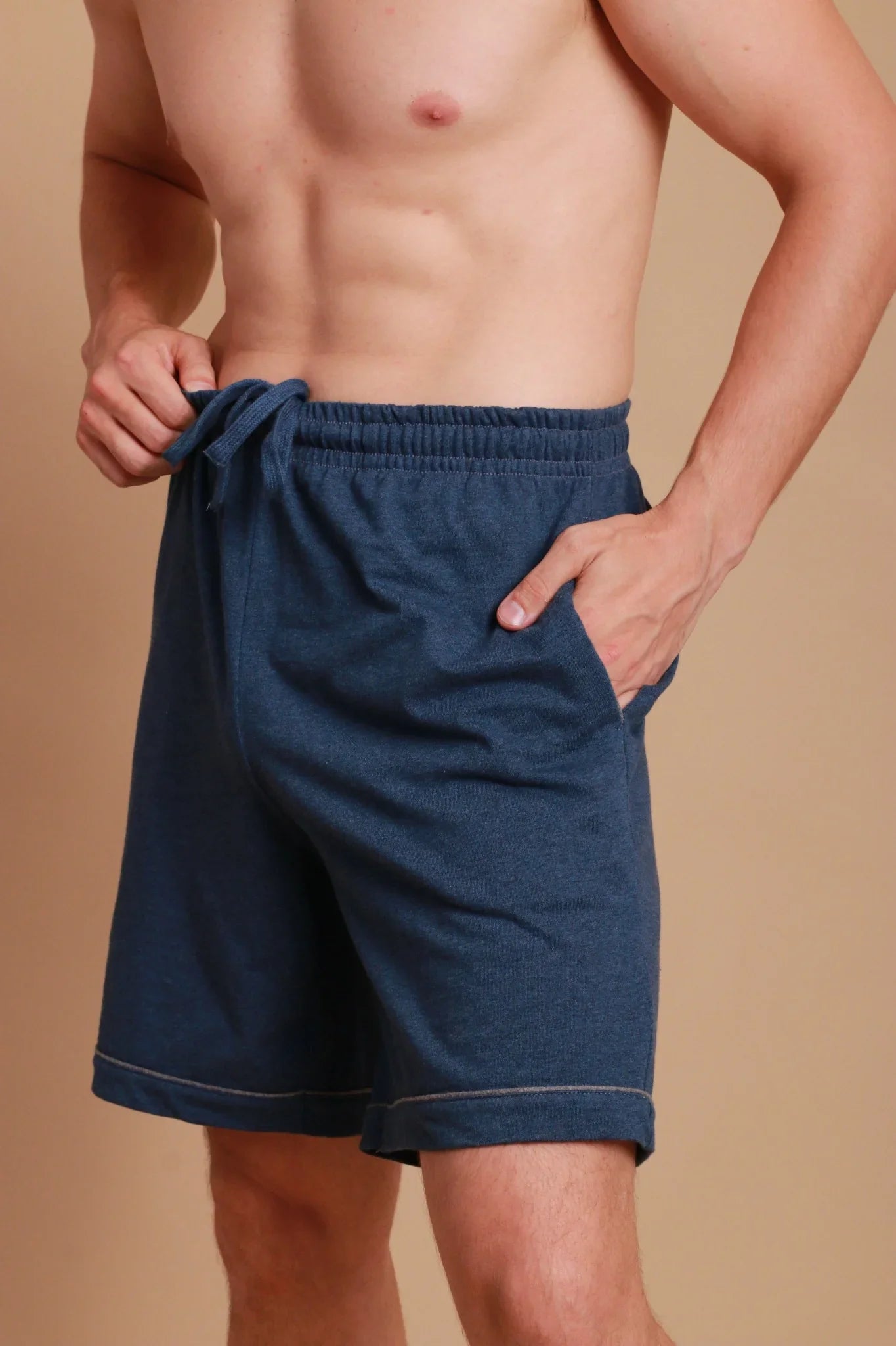 Man wearing blue hypoallergenic cotton shorts from Cottonique, showing waist tie and pocket