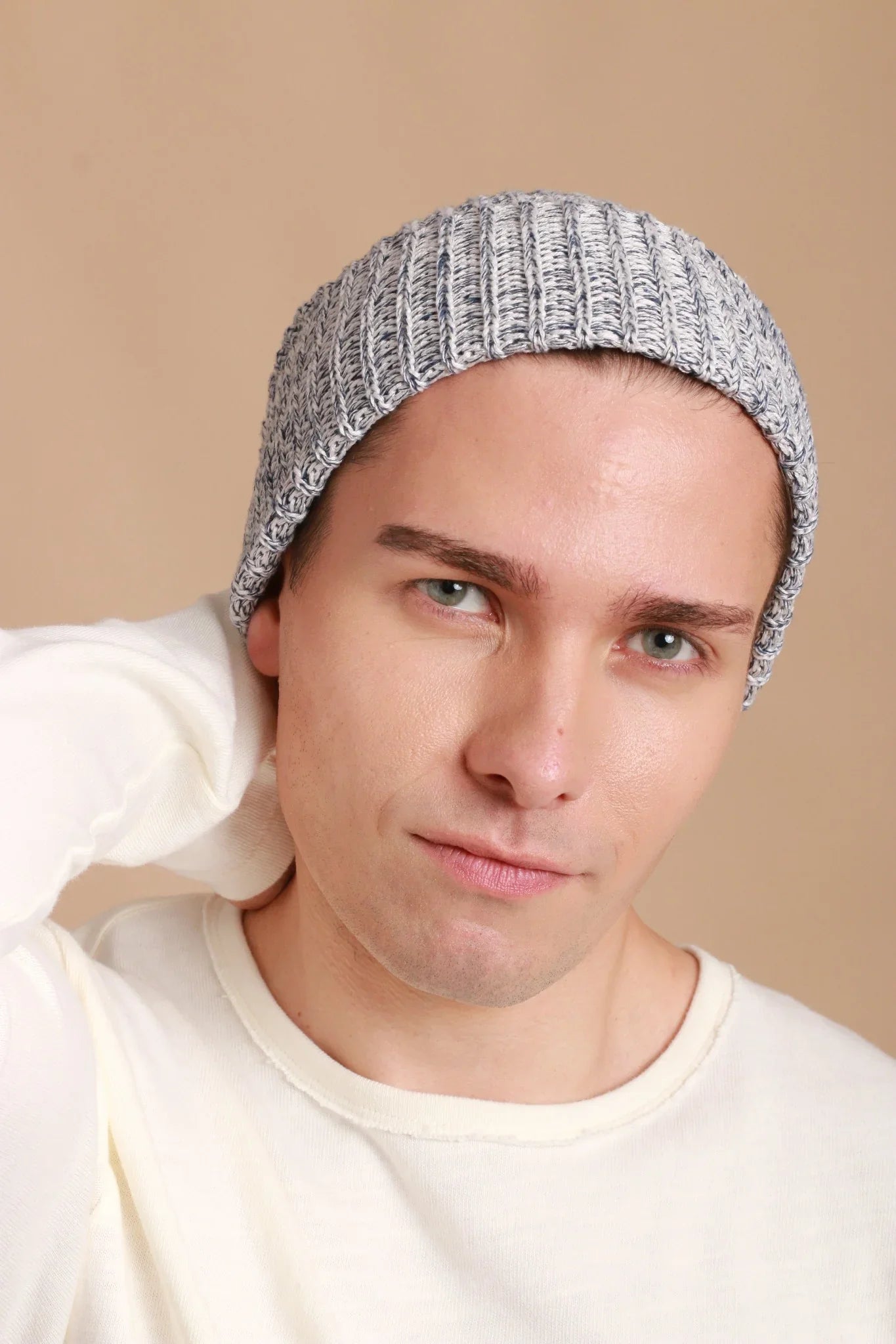 Man in hypoallergenic knit beanie and cream cotton shirt from Cottonique, neutral background