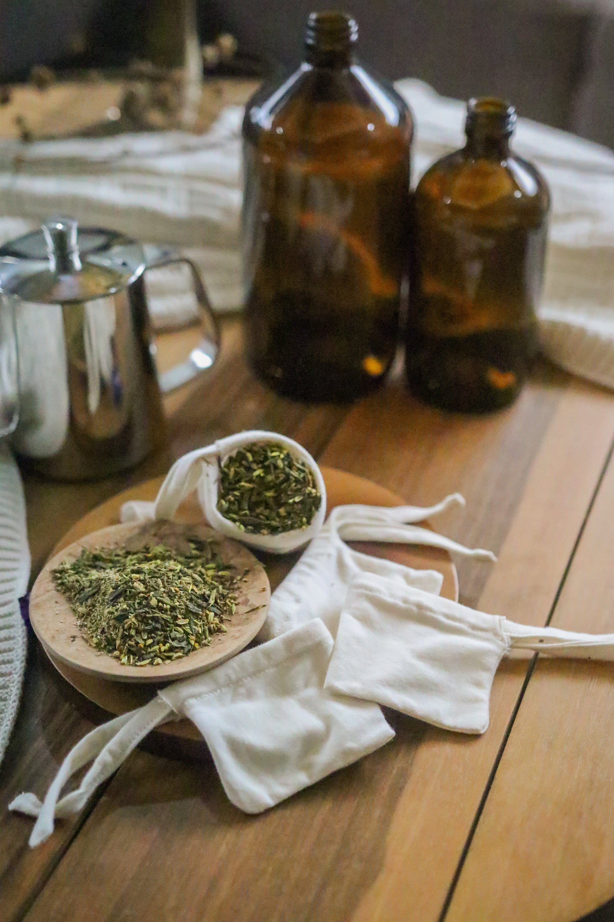 Reusable cotton tea bags with loose leaf herbs on a wooden table, allergy-free and zero waste.
