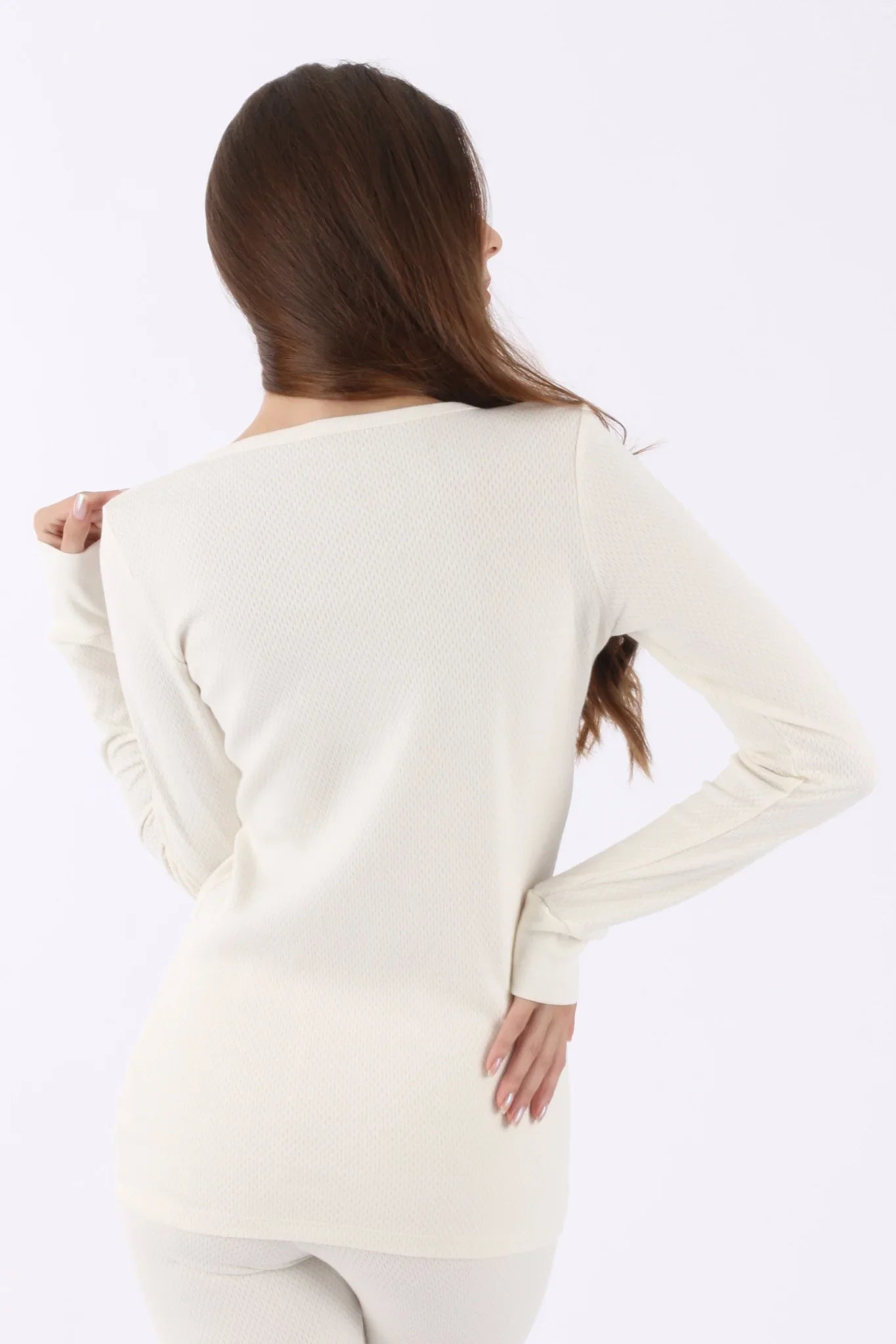 Back view of woman wearing long sleeve ivory organic cotton shirt and pants