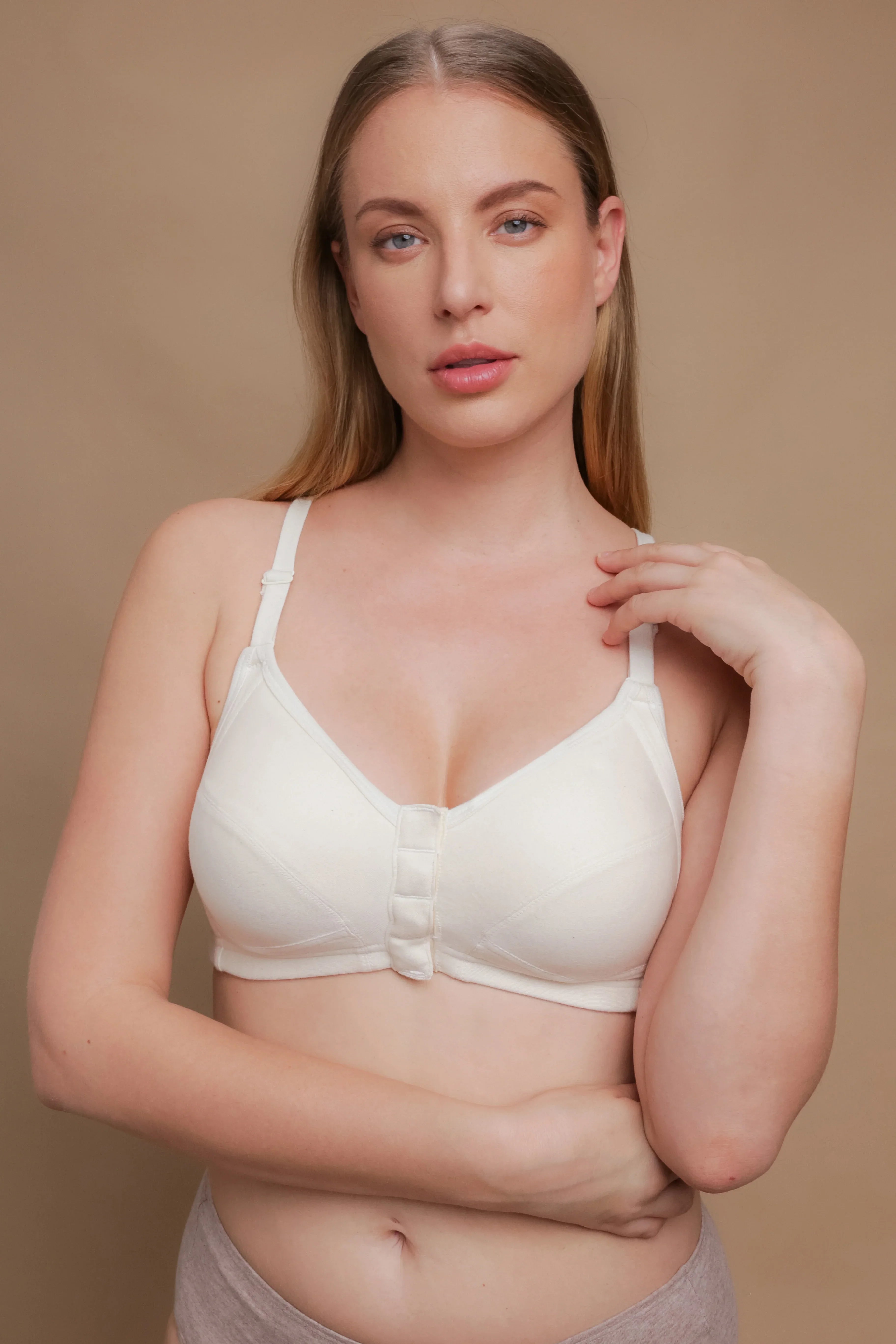 Woman wearing a front closure, allergy-free cotton bra by Cottonique on beige background