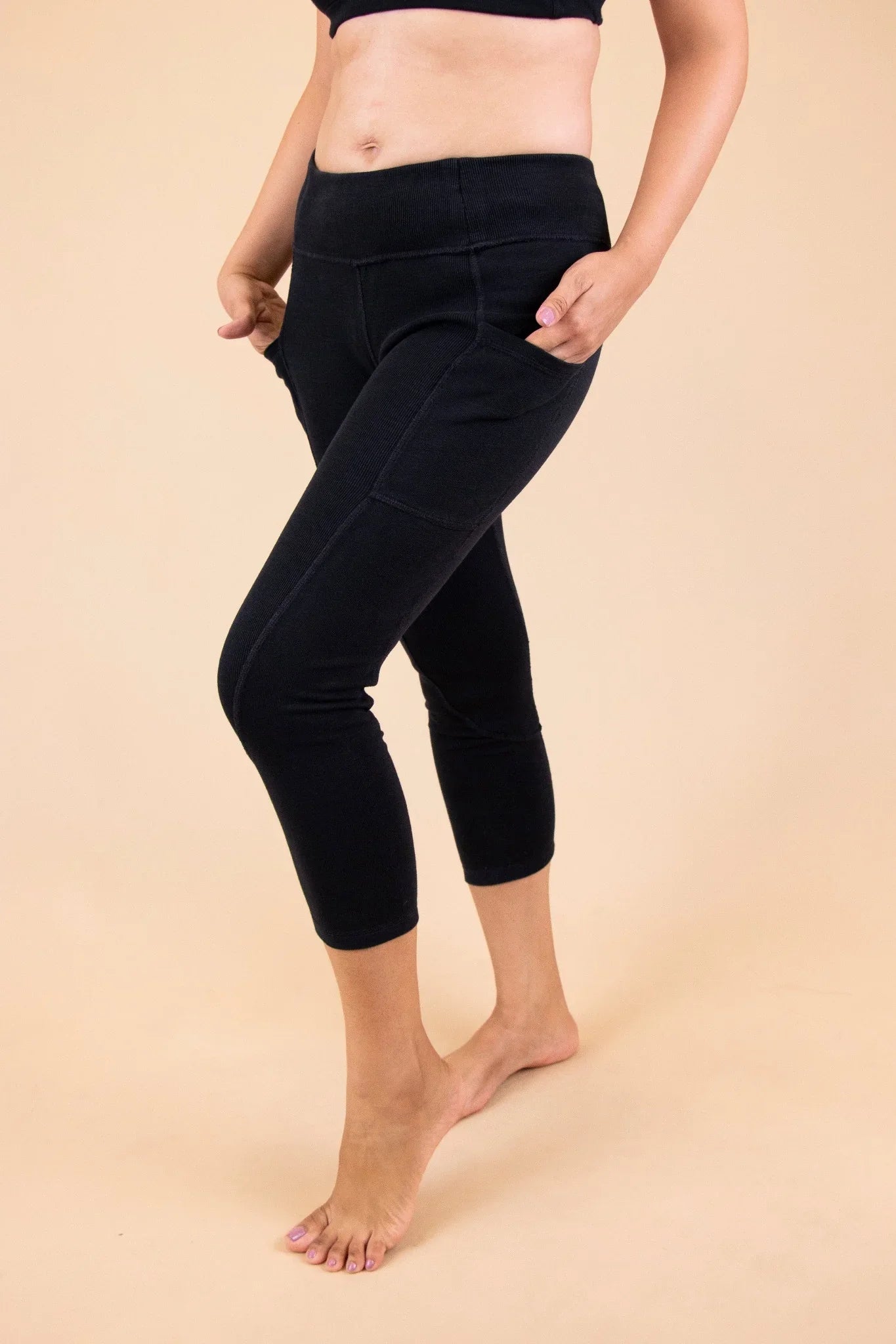 Woman wearing black organic cotton cropped leggings with pockets, ideal for sensitive skin