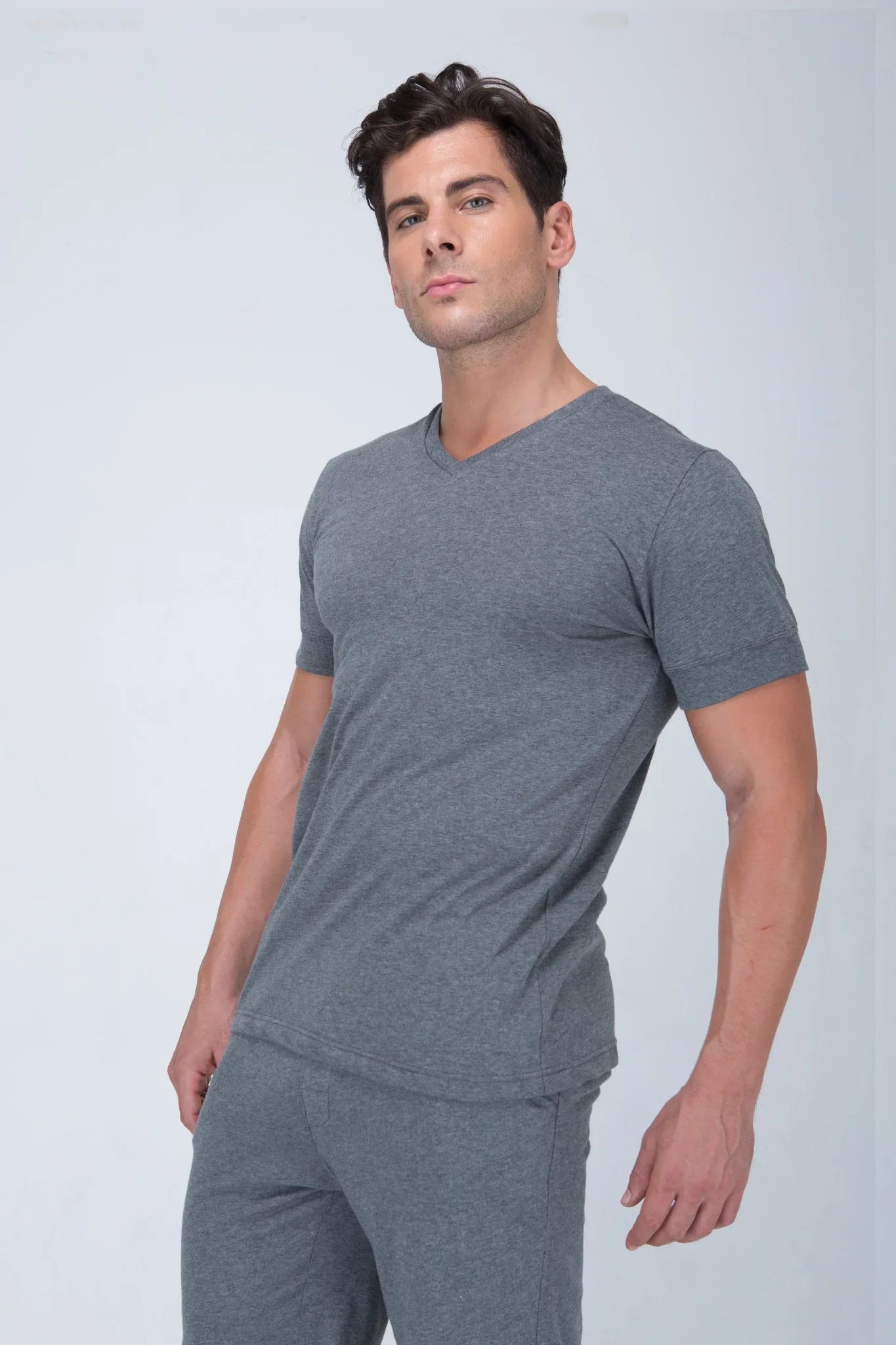 Man wearing grey organic cotton short sleeve V-neck t-shirt and pants, ideal for sensitive skin
