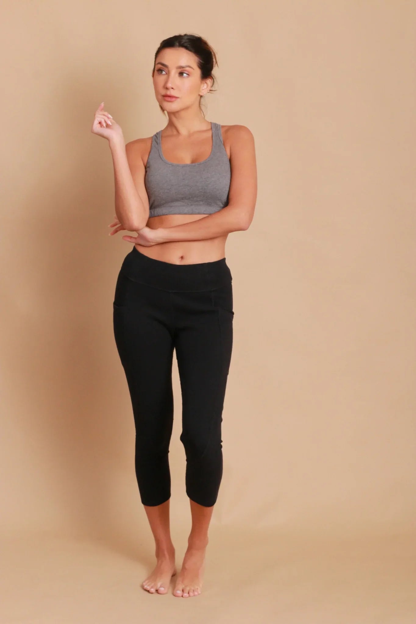 Woman wearing grey organic cotton sports bra and black cropped leggings, allergy-friendly clothing