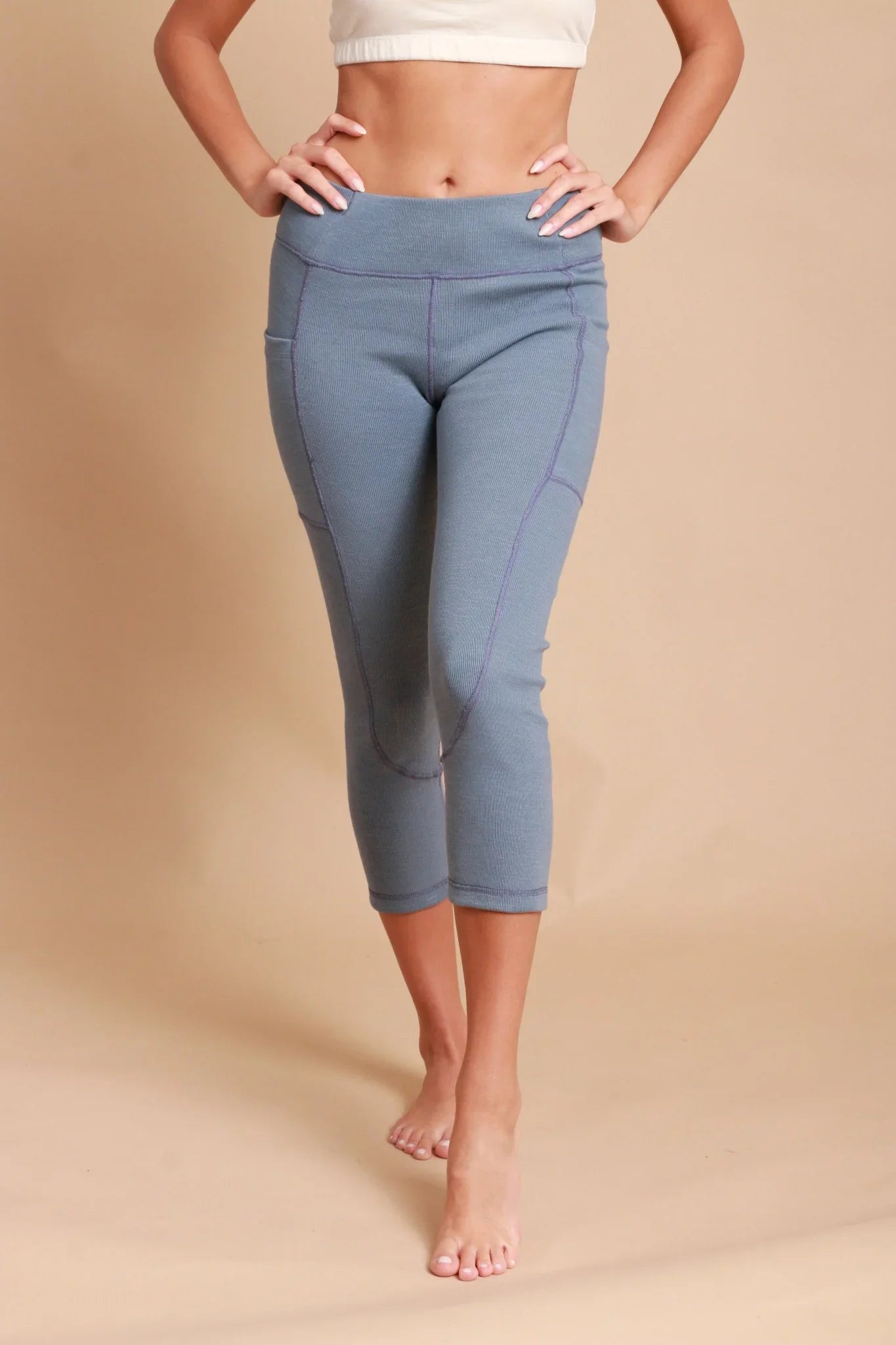 Woman wearing blue hypoallergenic cotton capri leggings from Cottonique on tan background