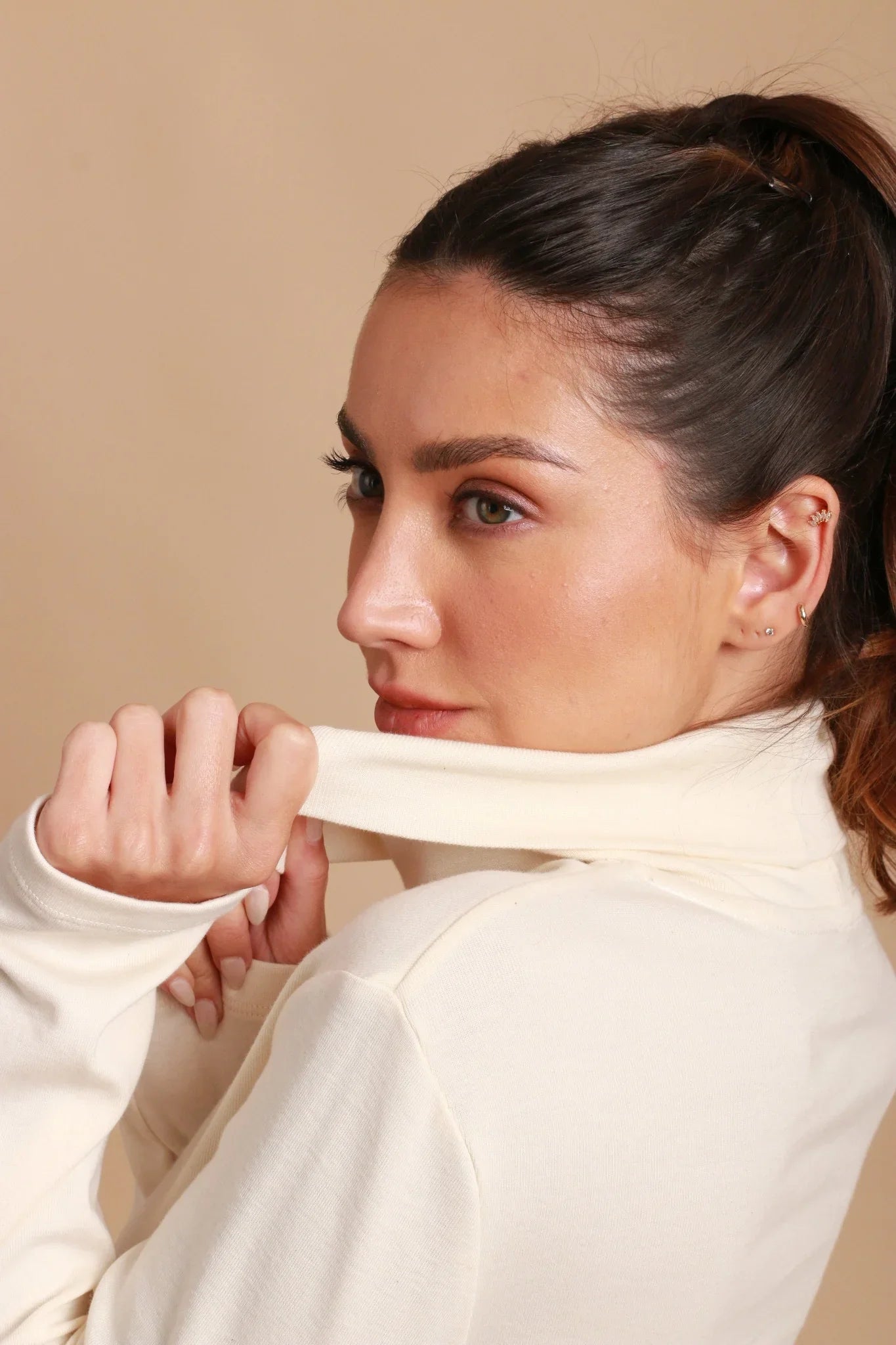 Woman wearing hypoallergenic cotton turtleneck top from Cottonique against beige background