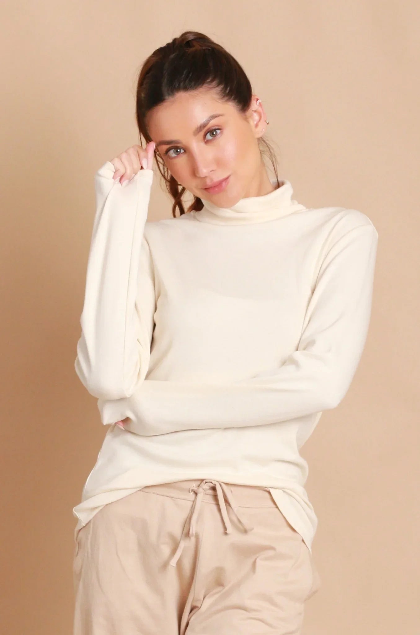 Woman wearing a cream hypoallergenic Cottonique turtleneck top and beige lounge pants