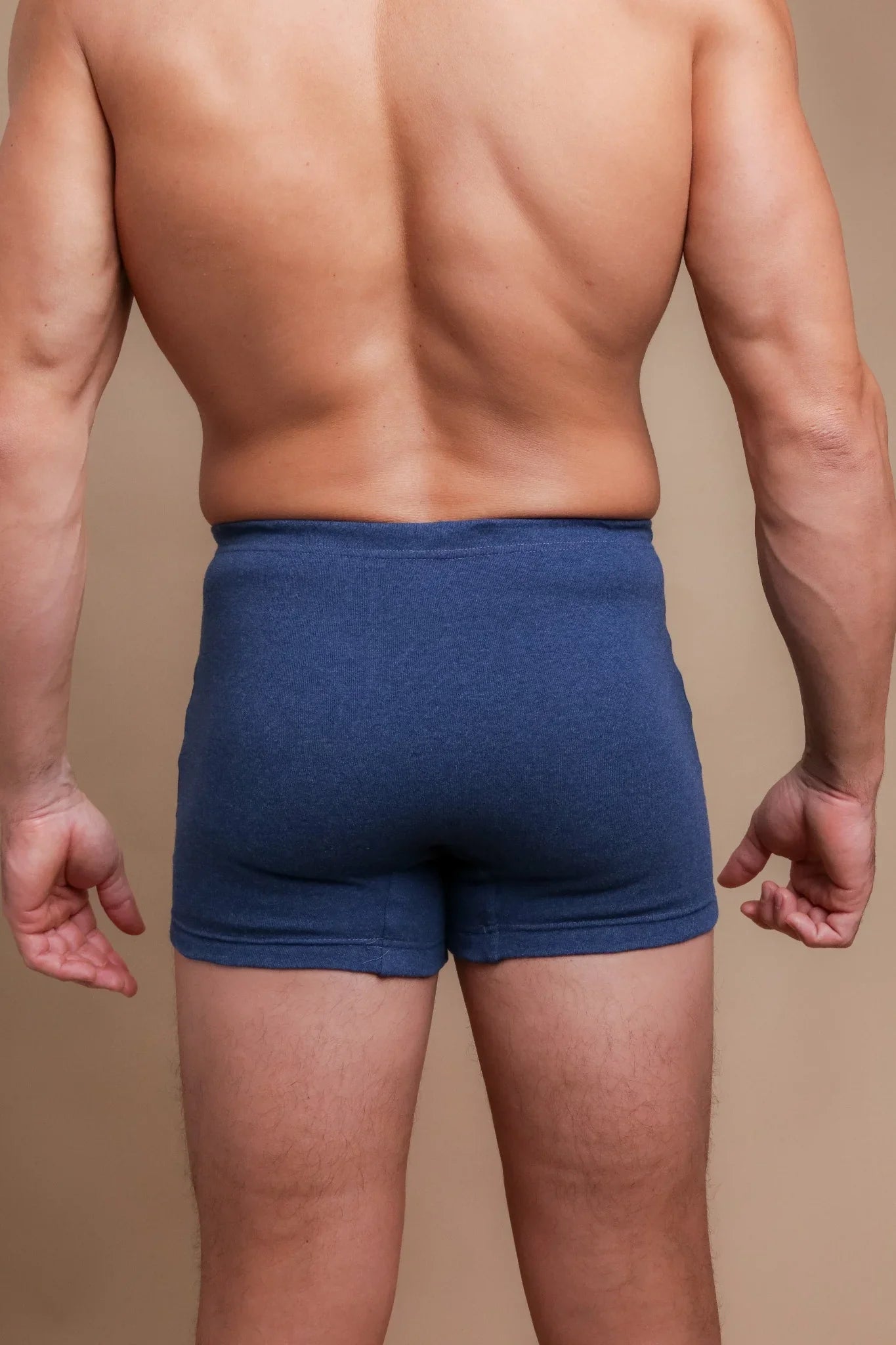 Back view of a man wearing blue hypoallergenic Cottonique underwear on a neutral background