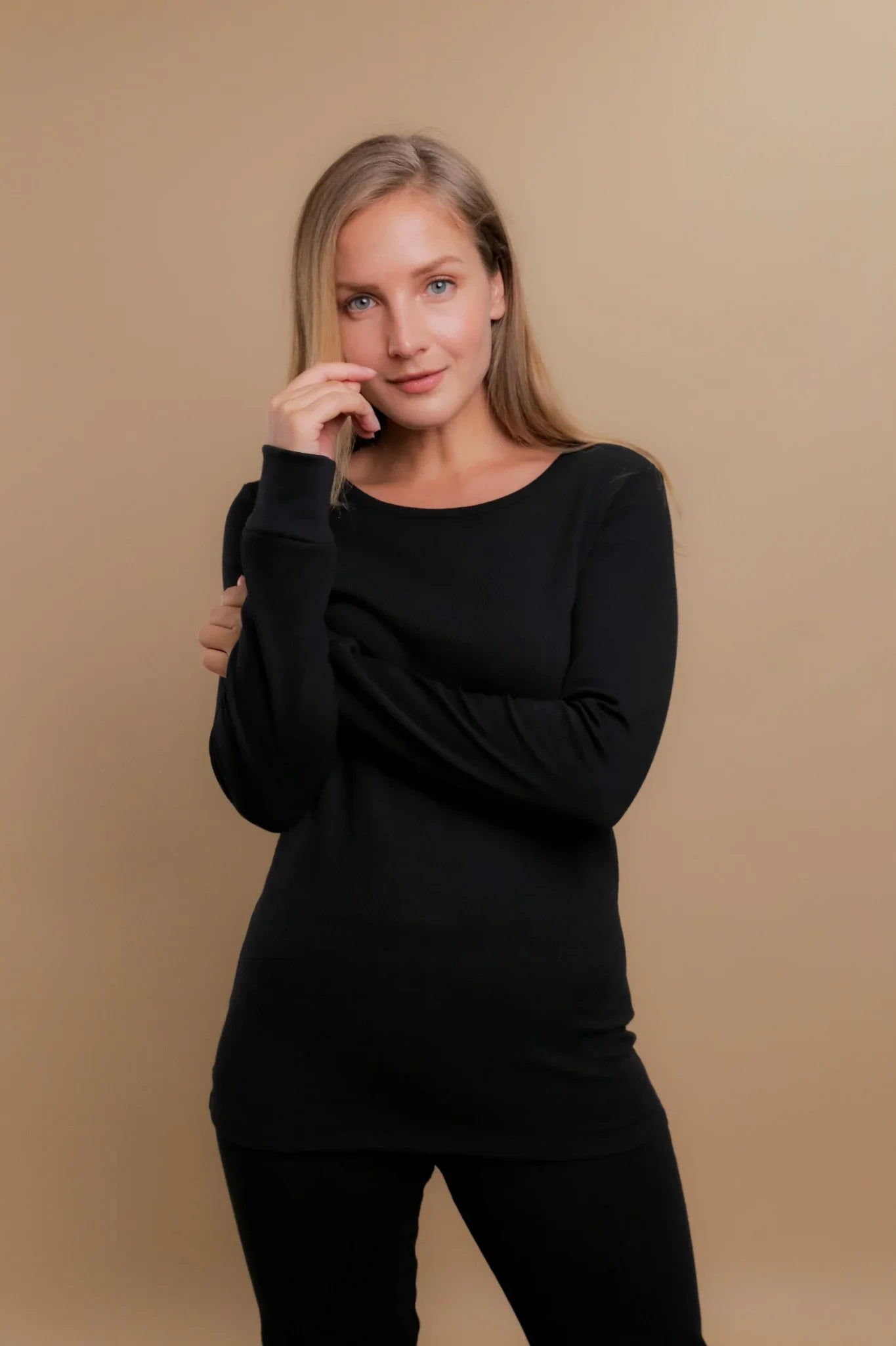 Woman wearing a black long-sleeve hypoallergenic Cottonique shirt against tan background