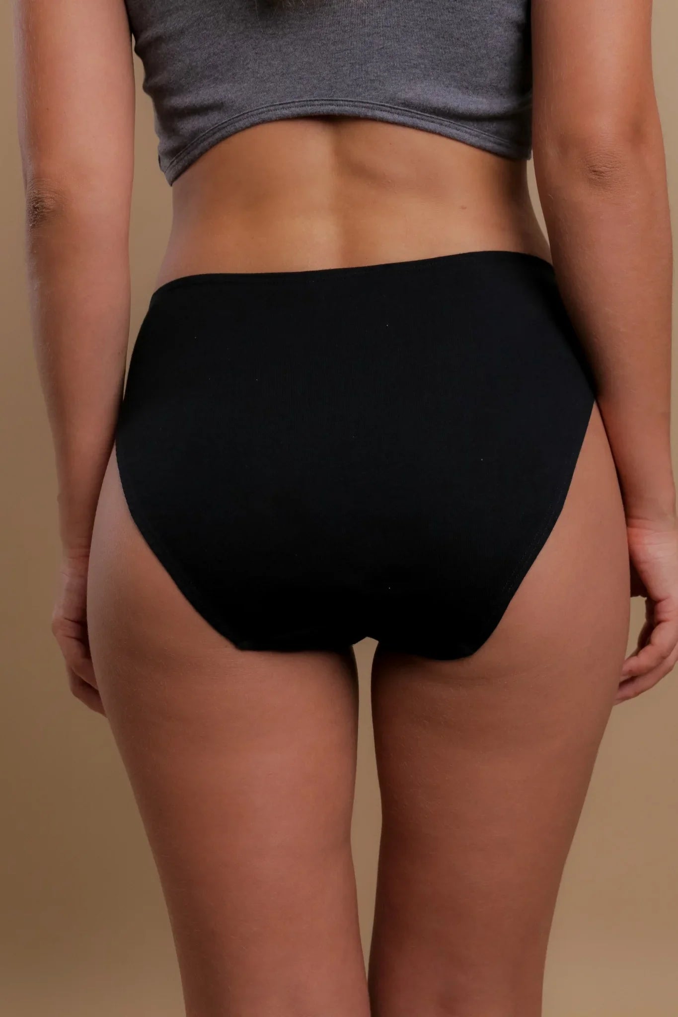 Back view of woman wearing black high-waist organic cotton briefs, eczema-friendly underwear
