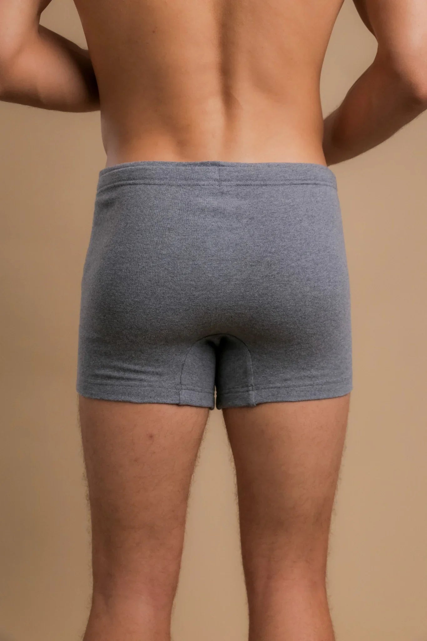 Back view of a man wearing gray organic cotton boxer briefs on a neutral background