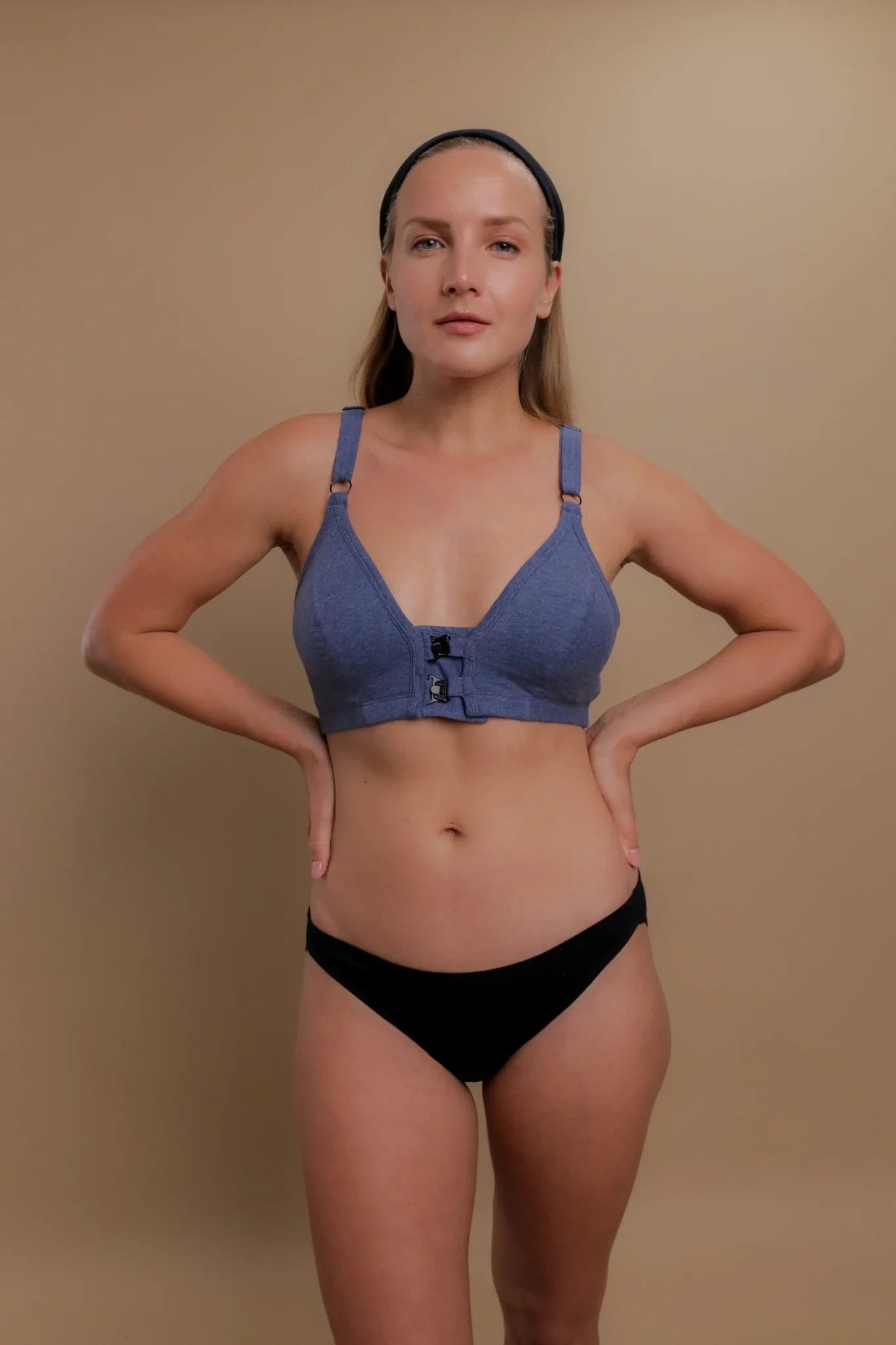 Woman wearing a blue front-closure organic cotton bra and black underwear for sensitive skin